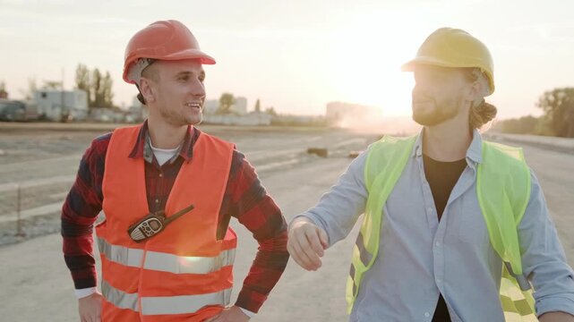 Smiling builders talking, controlling work process on site