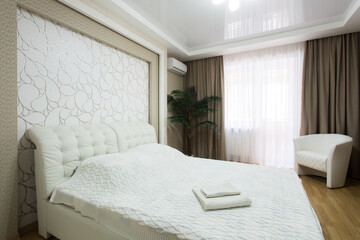 Obraz premium Comfortable powder pink chair next to shelf with firewood in soft pastel bedroom with decorative glass vases