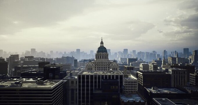 capitol dome framed by hazy skyline, drone vantage capturing historic dome and surrounding highrise under overcast sky, cinematic grain and muted palette convey
