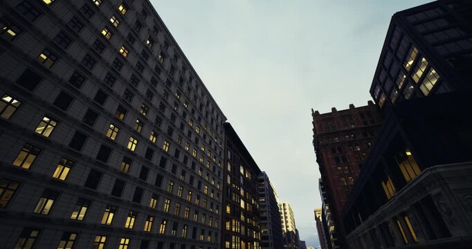 predawn urban avenue with early office lights and muted sky, towering facades framing empty road, contrast between lit interiors and cool exterior tones, quiet