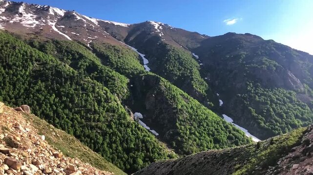 Chilam to Astore scenic route showing natural mountain landscape, snowy peaks, green hills, river-like stream, forest-covered slopes, and peaceful valley view captured from a high vantage point.