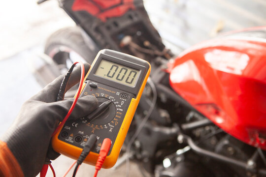 mechanic checking the voltage of a motorbike with a multimeter