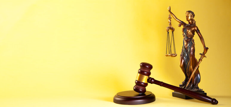 Law theme. Judge's gavel and scales of justice on yellow background.