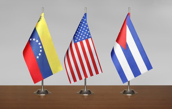 Three table flags Venezuela, USA and Cuba a blurred gray background