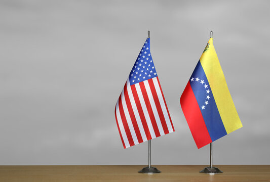 Two table flags of the USA and Venezuela on a blurred gray background