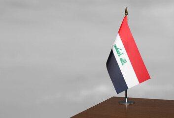 In the corner of the table, against a blurred gray background, stands the Iraq flag. © Halytskyi Olexandr