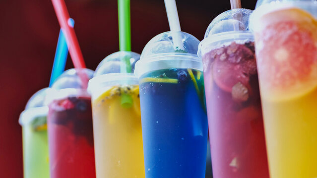 Row of various chilled fruit drinks with straws, perfect for a summer festival or event