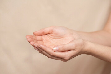 Woman cupped hands open in receiving gesture on beige