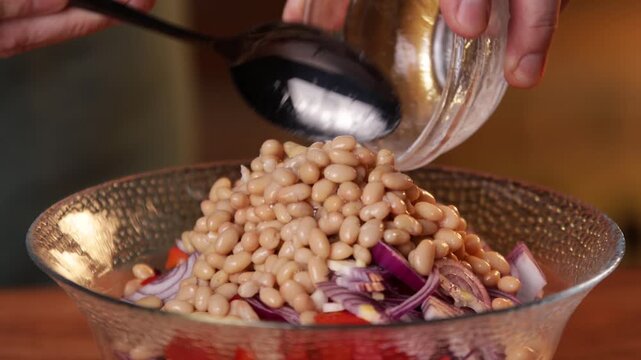 The cook adds white salt to the bowl with the salad and mixes the salad with a spoon.