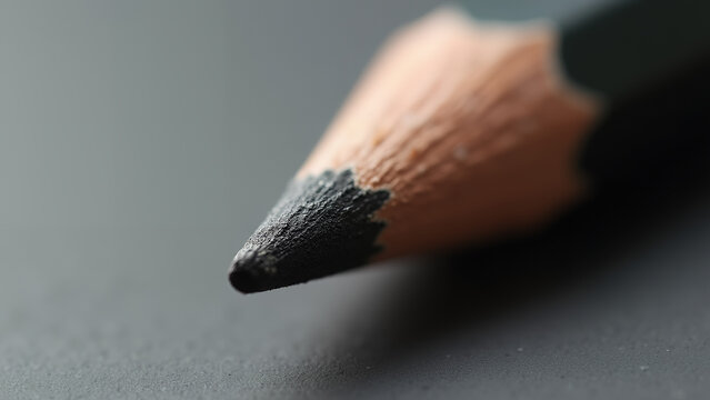A close-up macro of a sharp yellow graphite pencil and red eraser held in hand for drawing an art project with school education objects isolated on a white background