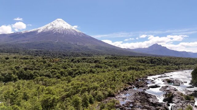 Aerial forward over the lush green canopy of Vicente P&eacute;rez Rosales National Park toward the iconic snow-capped cone of Osorno Volcano in the Los Lagos Region of Chile