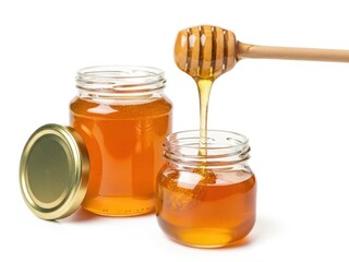 Golden honey flowing from a jar into another, showcasing its natural sweetness and viscosity.