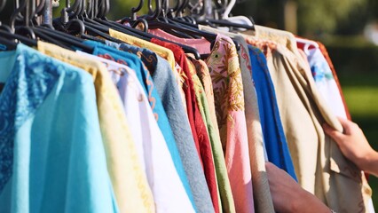 Hands browsing a rack of vibrant Indian ethnic clothing at a cultural festival