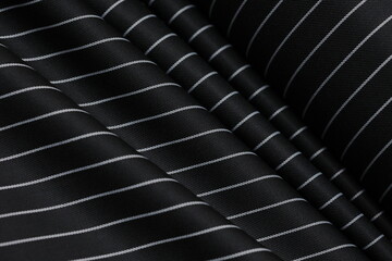 Obraz premium Premium black pinstripe suiting fabric with a professional wool-blend texture. High-quality textile featuring classic thin white stripes and elegant draping for luxury tailoring.