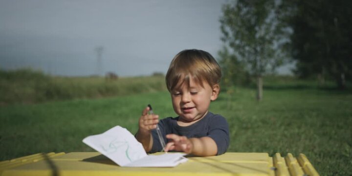 Young boy drawing at a table in the garden