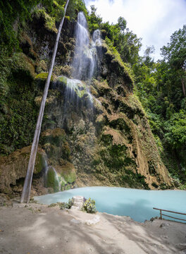 Tumalog Falls cascade off the high limestone cliff covered with lush vegetation to its turquise pool under, Cebu, the Filippines
