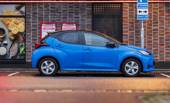 Gothenburg, Sweden - november 30 2025: Blue Toyota Yaris hatchback parked outside shop in evening light.