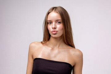 Fototapeta premium Young woman poses confidently in a studio with a plain background and minimalist style