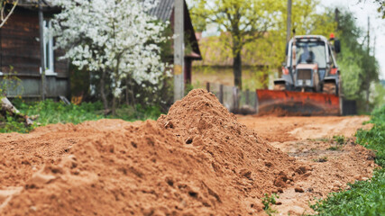 Bulldozer working on rural village road clearing soil for new infrastructure © Довидович Михаил