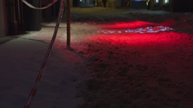 Frozen ground with cord fence and lighting. Detailed closeup of frosty rope barrier surrounding red patch on frozen surface