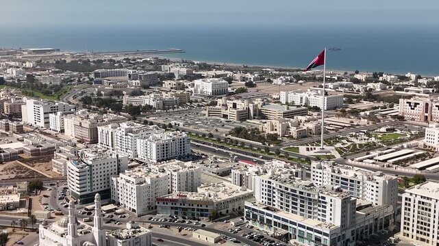 Muscat, Oman. Aerial drone view of the capital of Oman against the backdrop of the Gulf of Oman. Flight over the government district with many ministries and a huge Omani flag pole.