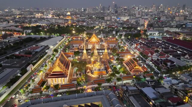 Bangkok, Thailand: Aerial night view of Wat Pho Thai Buddhist temple complex (Temple of the Reclining Buddha) in heart of Thai capital city, Grand Palace on horizon - landscape drone panorama