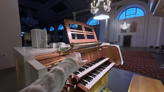 POV of hand turning on the overhead light for reading sheet music used on a pipe organ in a church.