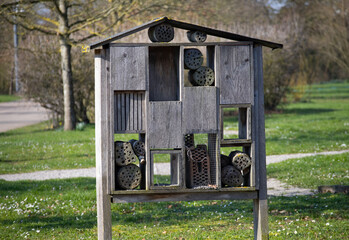 Large wooden insect hotel in a sunny green park field
