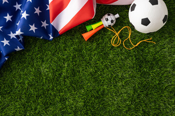 American soccer fan gear arranged on green grass with a US flag, vuvuzelas and a soccer ball suggesting national holiday celebrations and outdoor sports enthusiasm