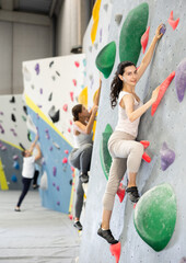 Fototapeta premium Athletic young woman practicing rock climbing on climbing wall..