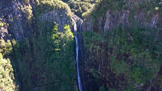 Drone flight through lush tropical canyon to a hidden waterfall, 25 Fontes area in Madeira Laurisilva forest, cinematic green nature landscape, 4K.