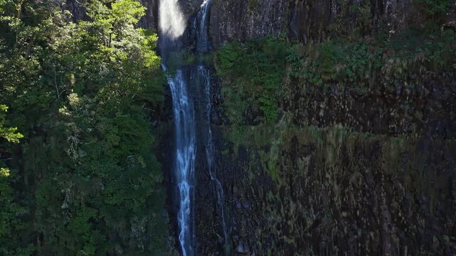 Breathtaking aerial view of a waterfall in 25 Fontes levada, drone flying near cascading water surrounded by lush green Laurisilva forest, Madeira, 4K.