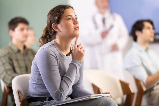 Attentive young girl watching presentation during a university lesson with senior doctor standing behind