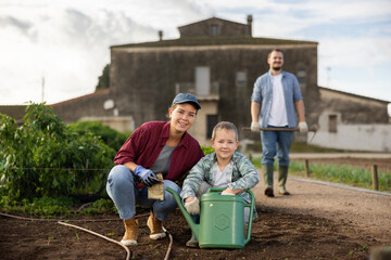 Fototapeta premium Family of farmers plant seeds in the garden. Growing organic vegetables on the farm