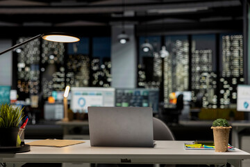 Modern empty office glows with the light of performance metrics and forecasting graphs. Corporate...