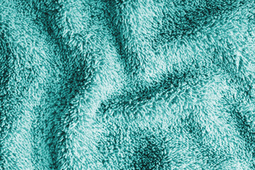 Close up, macro of crumpled turquoise terry towel fabric with wrinkles and soft waves. Fluffy microfiber texture with dense fibers, textile, material structure, detailed cloth abstract background © katyamaximenko