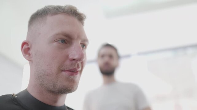 Professional barber cutting man's hair with electric clipper