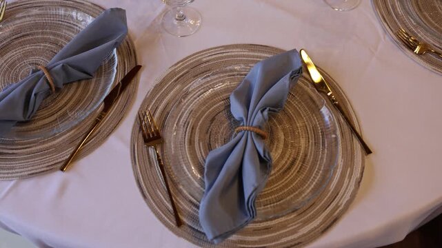 Elegant table setting with blue napkins and gold cutlery