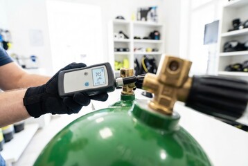 Obraz premium Technician using a digital oxygen analyzer to test the gas mixture inside a green scuba diving cylinder