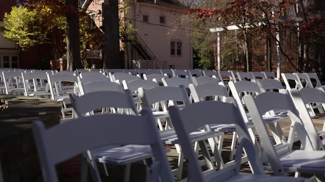 Outdoor wedding ceremony seating with white chairs and pergola