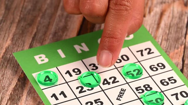 Hand placing green plastic chip on a bingo card during a game