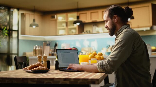 Software developer at home, writing code and debugging applications, IT engineering on command-line interfaces. Focused digital work ensures software maintenance, laptop in the kitchen.
