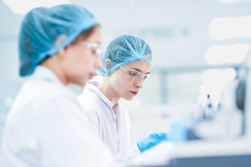 Scientific research team collaborating on experiment project. Female scientists in ppe gear...