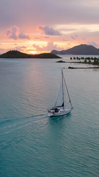 Sailboat cruising along tropical island coast during sunset