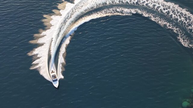 Overhead aerial view of speedboat turning in blue water