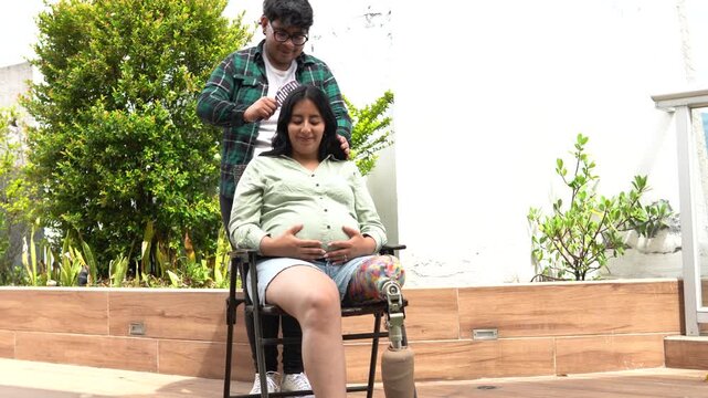 Man combing hair of pregnant woman with prosthetic leg