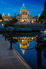 Fototapeta premium Victoria Parliament Building Inner Harbour Morning Reflection vertical. Victoria's Inner Harbor and marina in downtown Victoria. The historic Legislative Building at night looks over the harbor.
