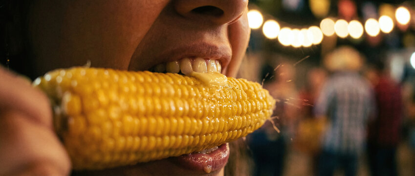 A close-up of a person eating corn on the cob