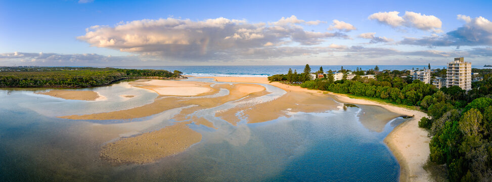 Aerial panorama of an inland lake draining out through tidal channels and narrow opening to the sea