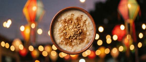 Naklejka premium A cup of coffee with nuts and cinnamon sprinkled on top, surrounded by colorful lanterns and bokeh lights